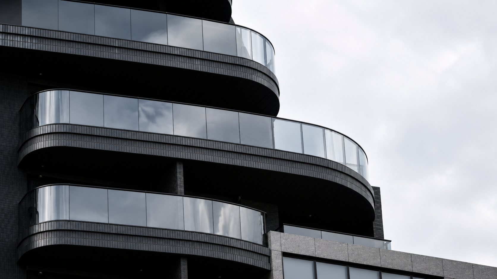Architectural glass railing on a modern curved balcony façade